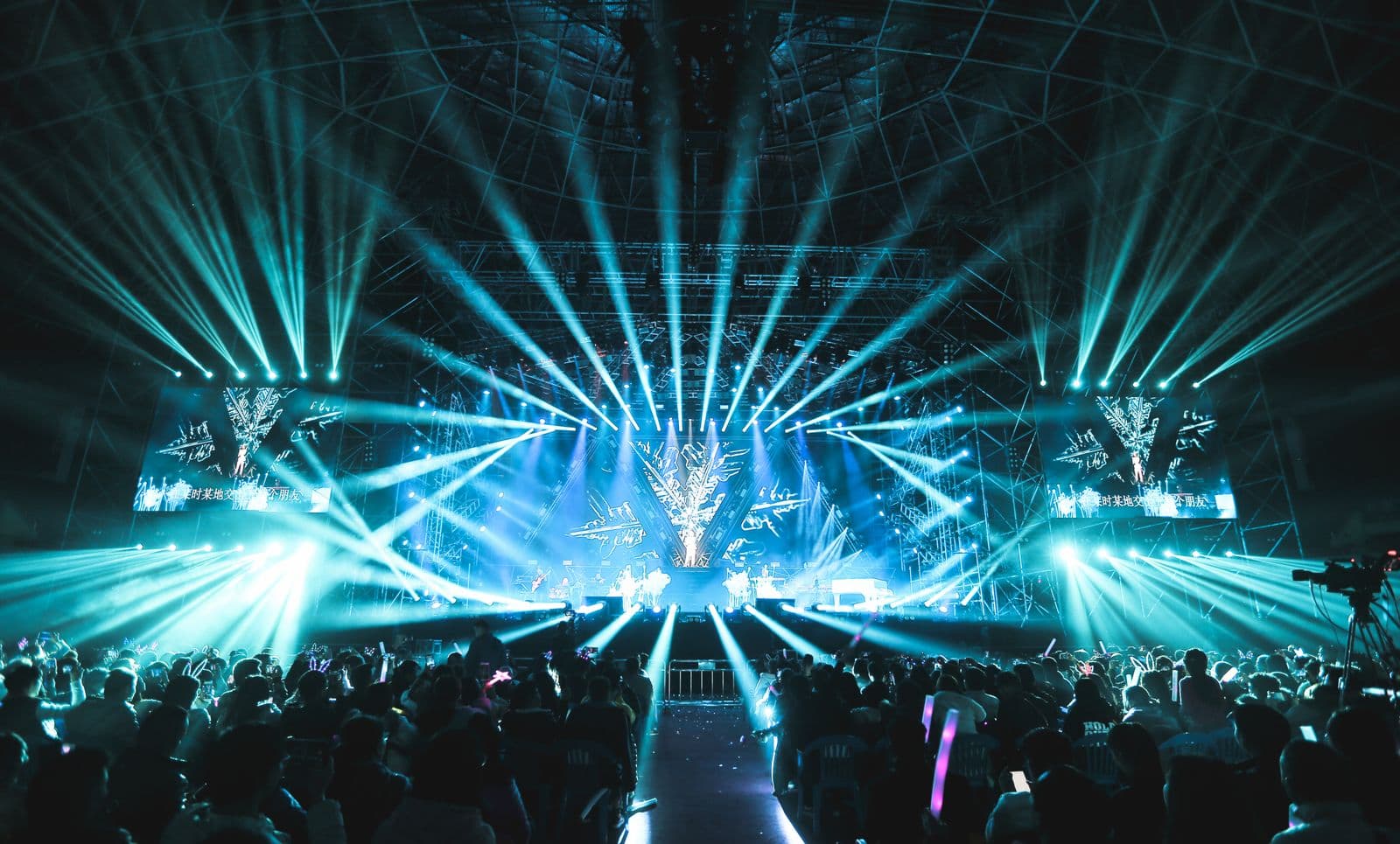 Scène de concert traversée de faisceaux lumineux, matériel son et lumière déployé par un prestataire technique